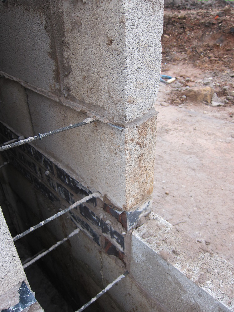 The "double damp" - two layers of damp-proof-course membrane, one immediately above the blue bricks and one just visible above the first block - which gives the option to bring the external ground level up to the top of the blue bricks to match the internal floor level